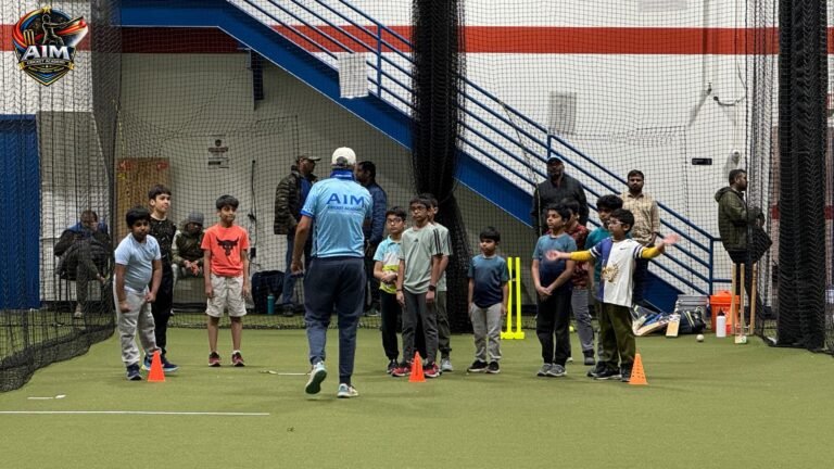 Cricket coach instructing group of young players during indoor training session with cones and drills