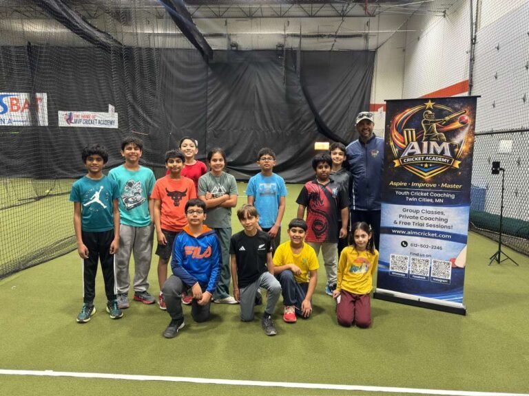 Group of young cricketers with coach at AIM Cricket Academy indoor training facility